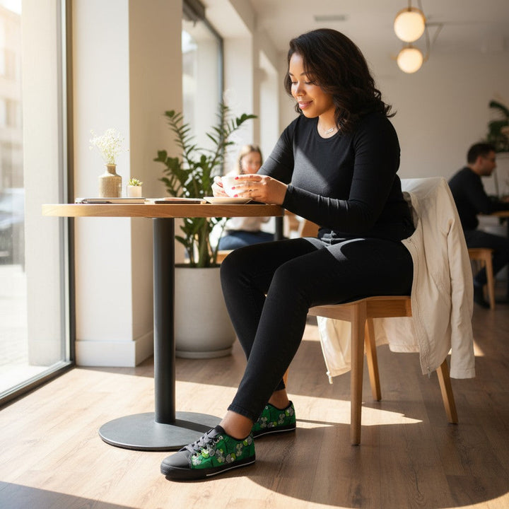 Femme assise dans un café portant des baskets KAKIPS Évasion Lagos en toile verte à motifs wax africains